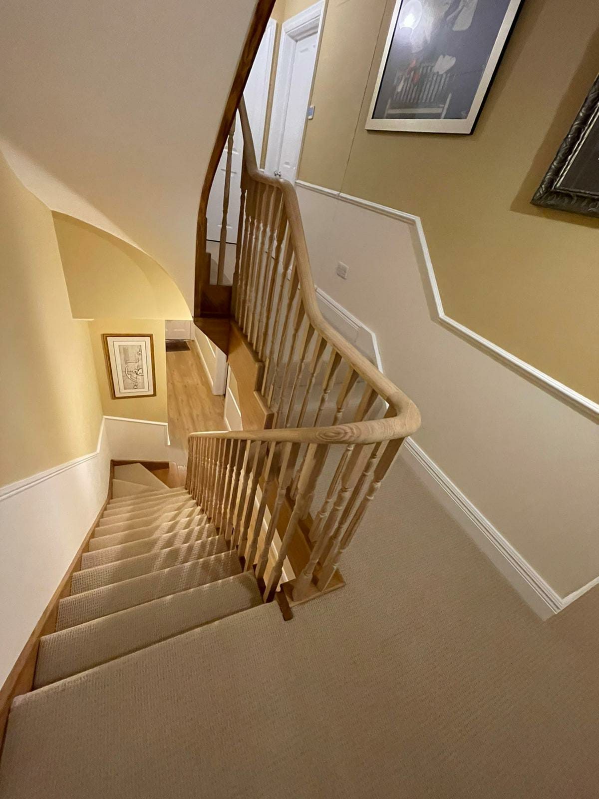 Oak handrail curving around a carpeted staircase