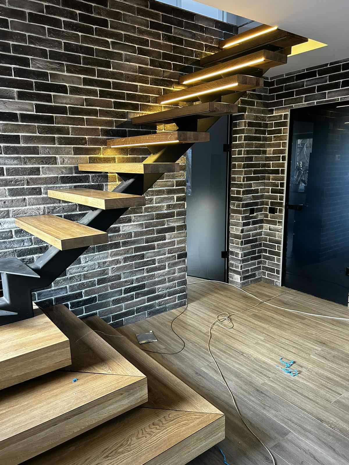 Floating oak staircase with LED lighting on a brick wall