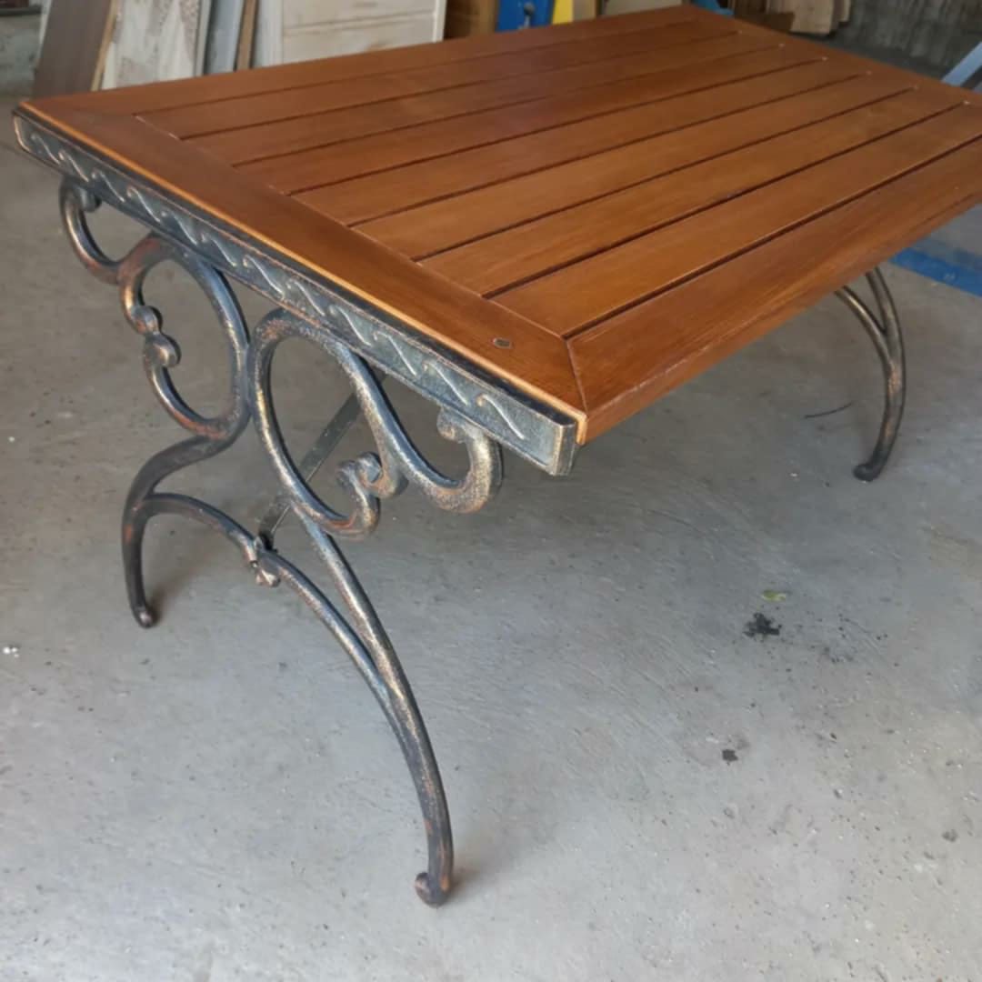 Slatted timber table on an ornate iron base