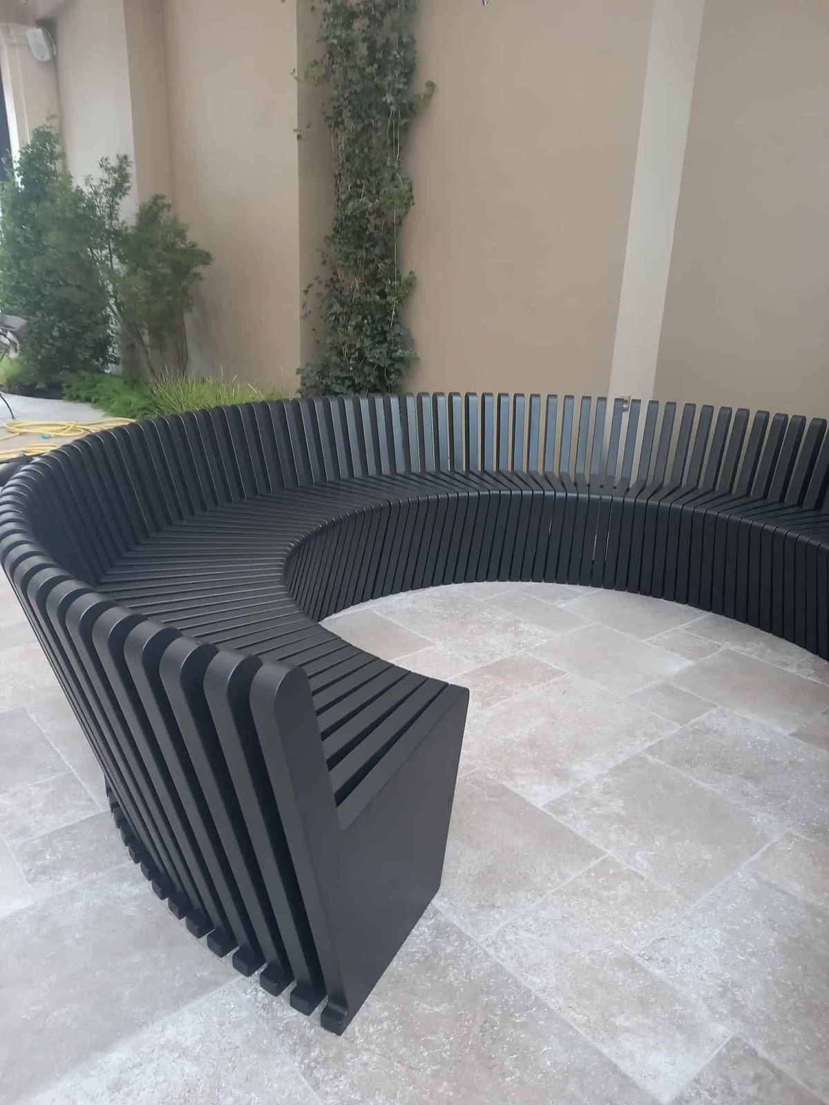 Curved slatted bench in black timber